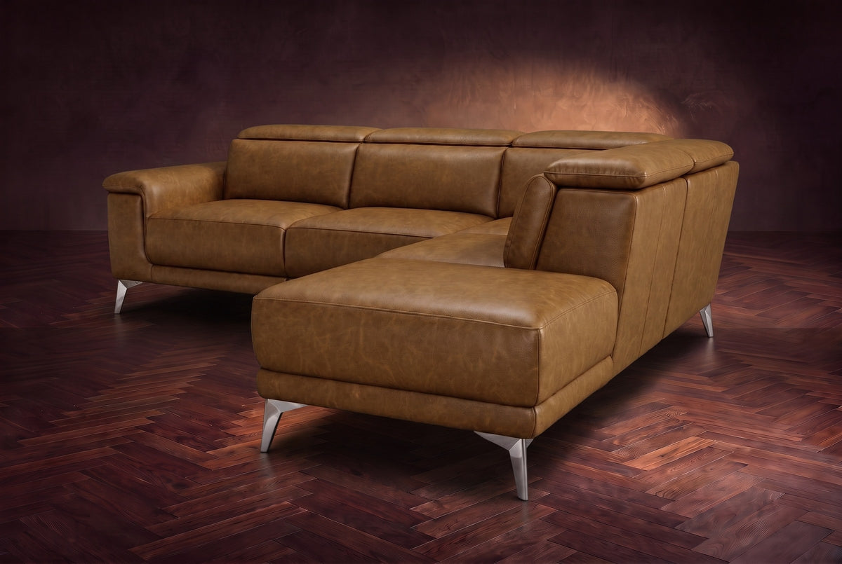 The Pista sectional in Weathered Saddle distressed full leather on a dark walnut herringbone floor against a brown plaster wall, seen from the chaise end, headrests down and footrest closed. Shown in Weathered Saddle, Right chaise.