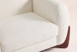 Close-up of the Beige boucle seat cushion and the rounded arm above a walnut wedge foot