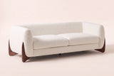 Pistoia Boucle Sofa in Beige boucle, three-quarter view on a warm off-white backdrop, with its sculpted walnut wedge feet