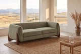 Pistoia sofa in Olive Green boucle in a sunlit room with the Calgary foothills through tall windows and a jute rug
