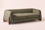 Pistoia Boucle Sofa in Olive Green boucle, three-quarter view on a warm off-white backdrop, with its sculpted walnut wedge feet
