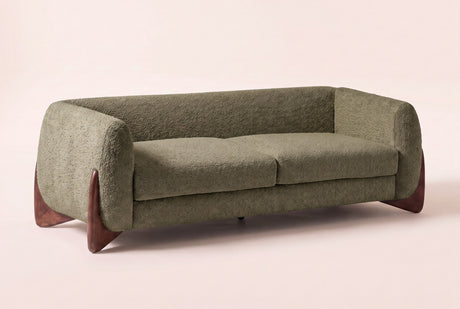 Pistoia Boucle Sofa in Olive Green boucle, three-quarter view on a warm off-white backdrop, with its sculpted walnut wedge feet