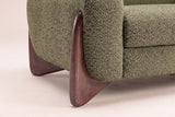 Close-up of the sculpted walnut wedge foot hugging the Olive Green boucle arm of the Pistoia sofa