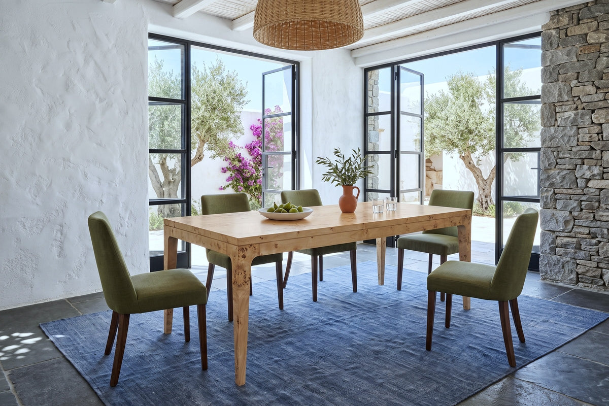 Polcenigo dining table in Honey Blonde Burl in a Greek island villa, with white lime plaster, a fieldstone wall