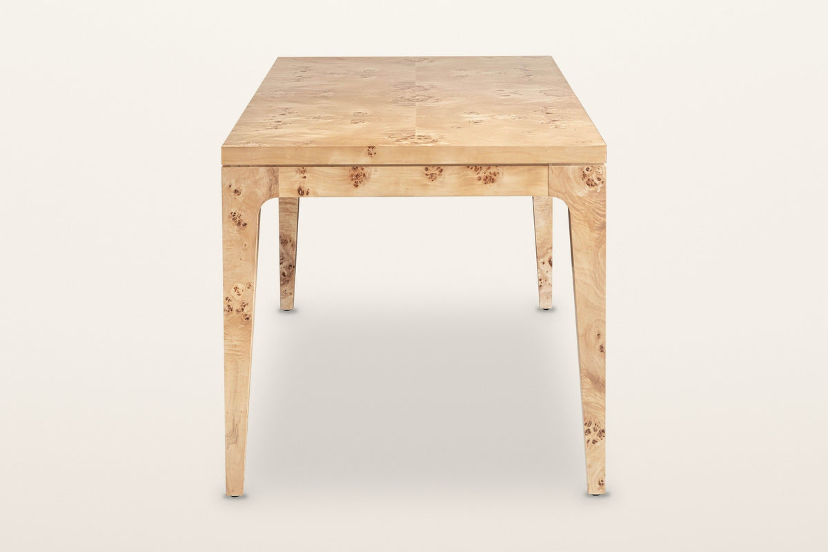 End view of the Polcenigo dining table in Honey Blonde Burl on a warm white studio backdrop: the curved knees where each leg