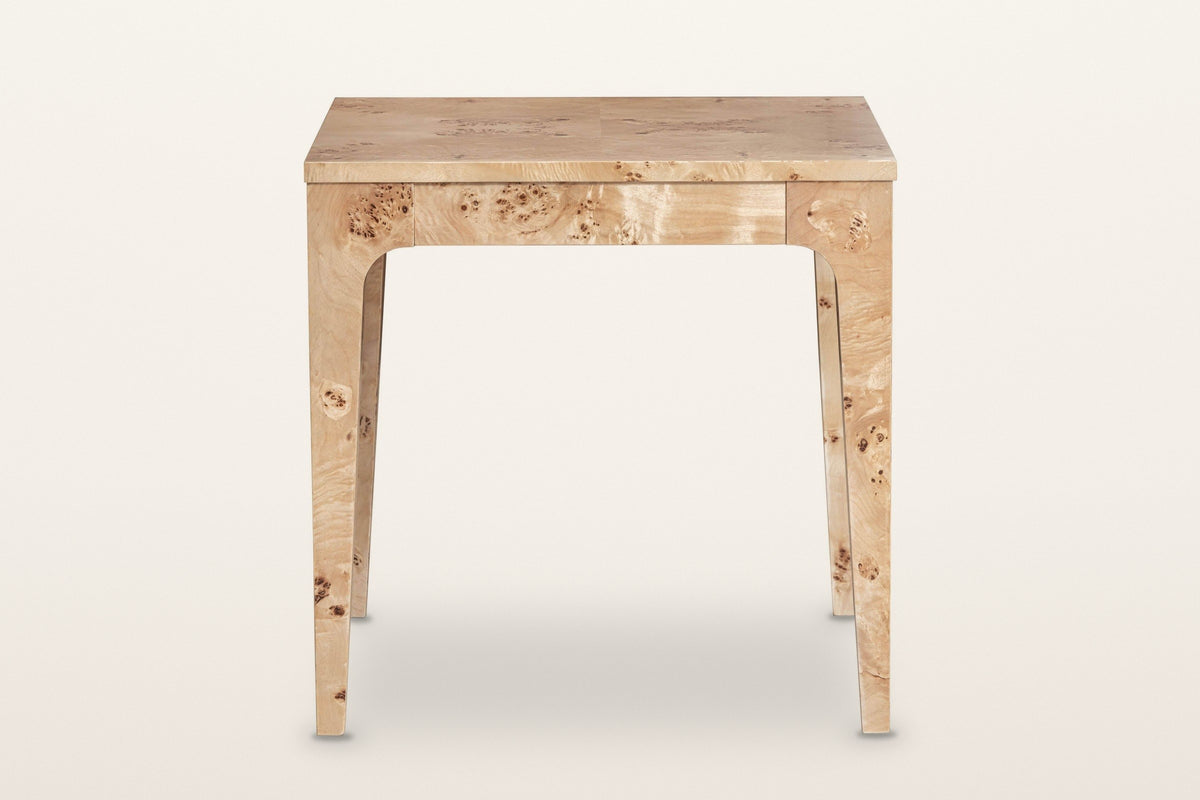 Polcenigo side table in Honey Blonde Burl, front view on a warm white studio backdrop: the apron and two legs curving into it