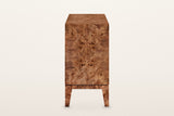 Polcenigo sideboard in Dark Burl, end view on a warm white studio backdrop: a book-matched burl end panel over the rail and t