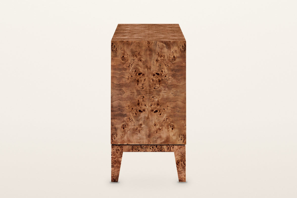 Polcenigo sideboard in Dark Burl, end view on a warm white studio backdrop: a book-matched burl end panel over the rail and t