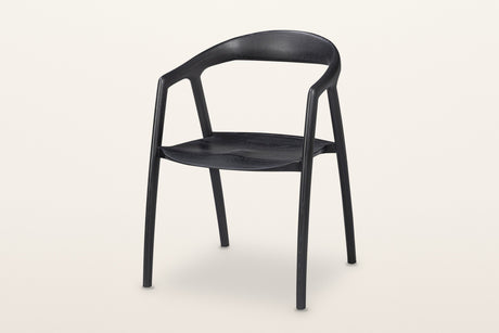 Pollica solid ash dining armchair in Black, three-quarter view on a warm white studio backdrop