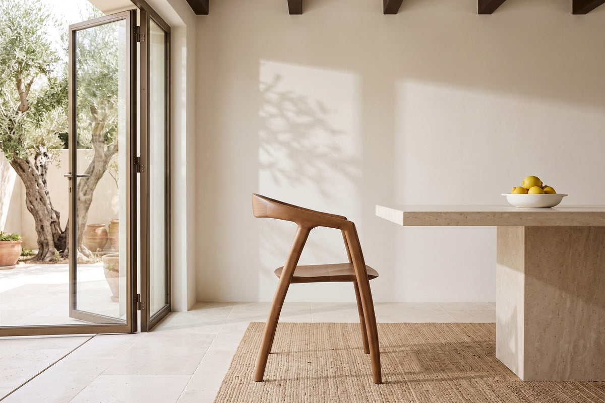 A Pollica dining chair in Caramel in side profile at a limestone table in a Corfu villa, with lime plaster