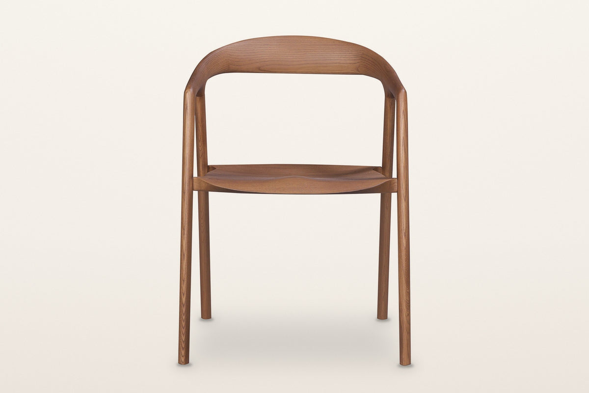 Pollica dining chair in Caramel, straight front view on a warm white studio backdrop: the band
