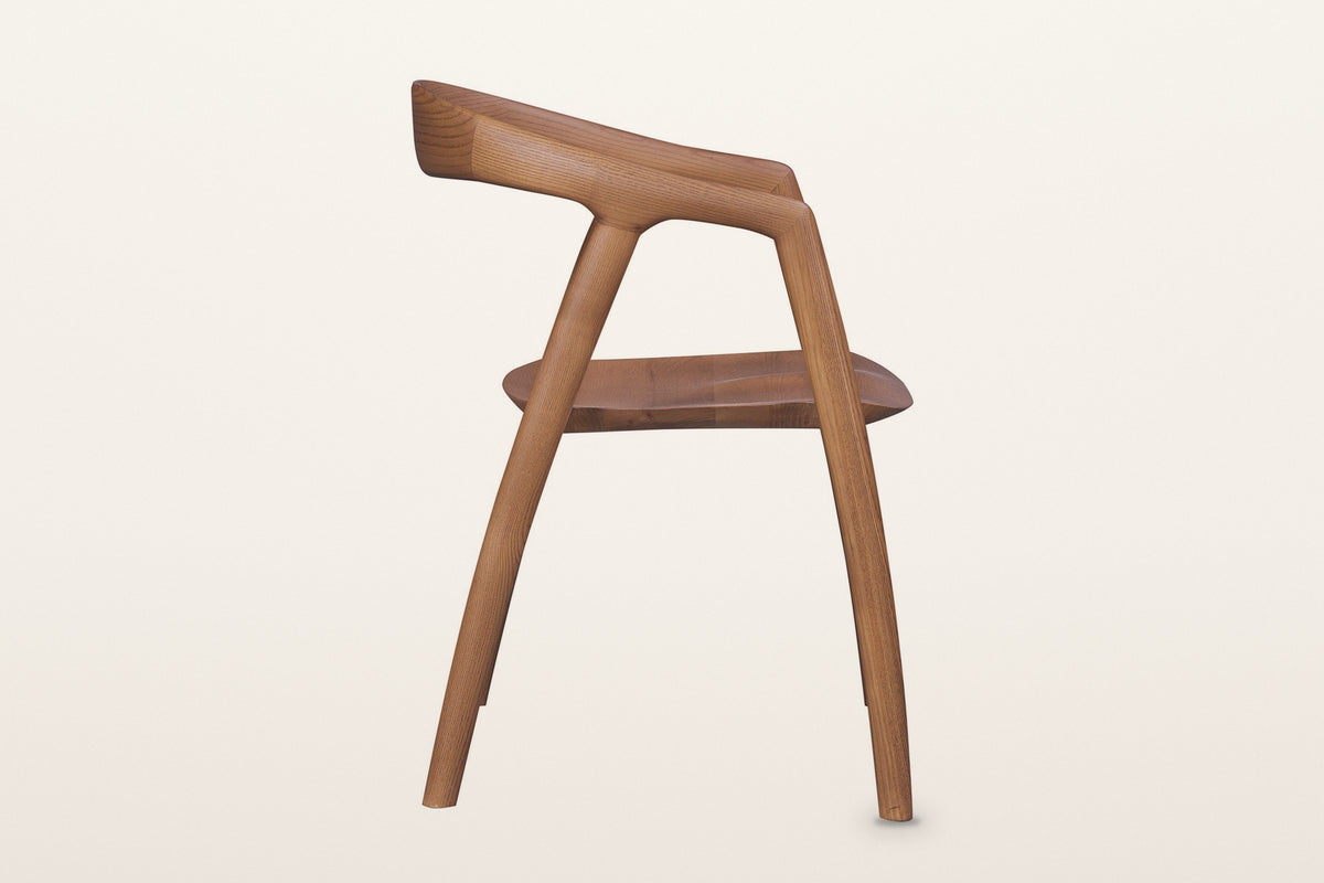 Pollica dining chair in Caramel, side view on a warm white studio backdrop: the legs lean in like an A and the band reaches b