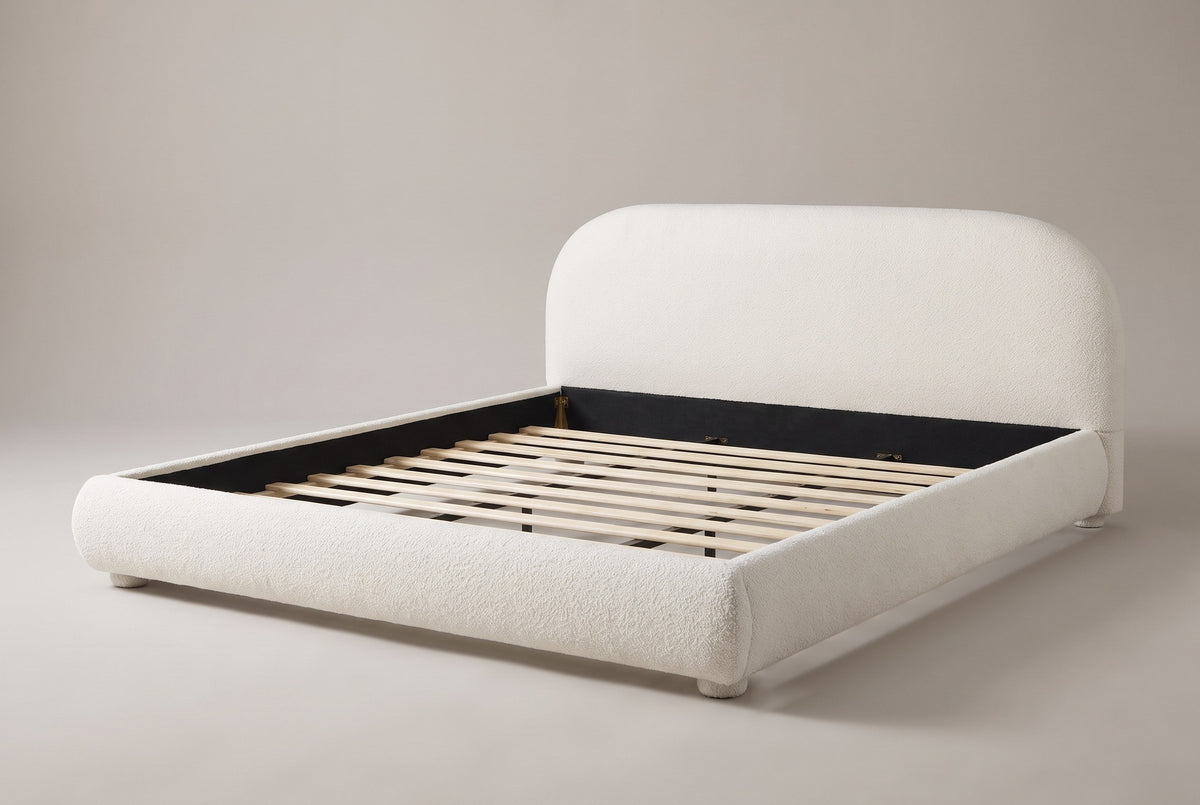 Pollutri upholstered bed in cream white boucle, three-quarter view on a warm grey studio backdrop