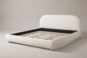 Pollutri upholstered bed in cream white boucle, three-quarter view on a warm grey studio backdrop