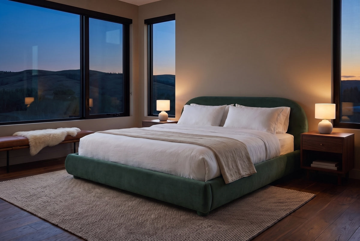 Pollutri bed in dark green velvet in a bedroom at dusk, two lamps lit, dark foothills through the windows