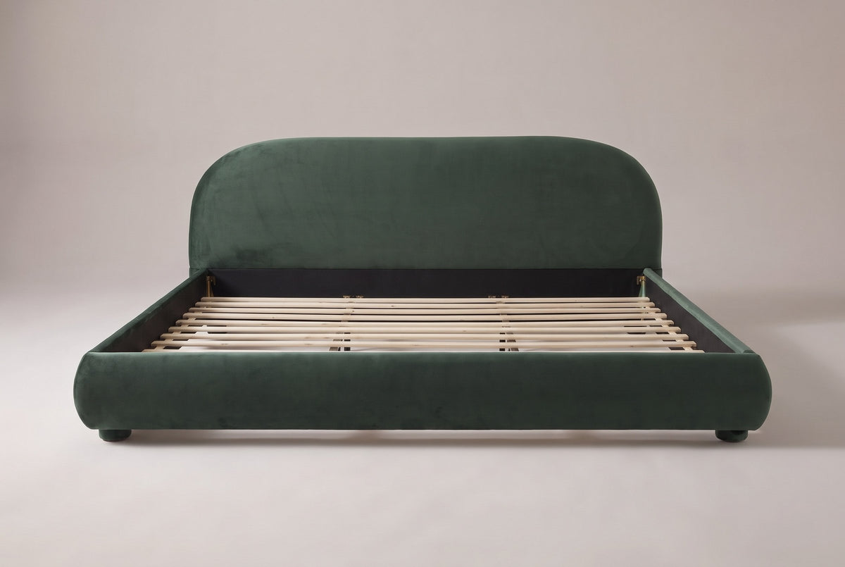 Pollutri upholstered bed in dark green velvet, straight front view on a studio backdrop