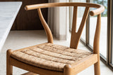 Close-up of a Poppi chair in Brown: the curved top rail with its rounded ends, the Y-shaped splat and the abaca seat