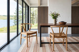 Two Poppi dining chairs in Brown at a walnut table on a black steel base in an Elkwater lake house