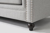 Close-up of the arm front with two lines of silver nailheads and a turned espresso bun foot