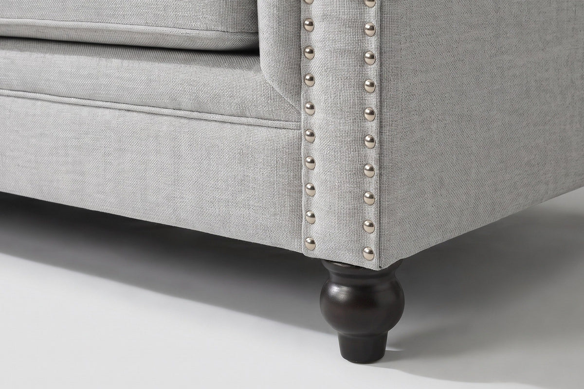 Close-up of the arm front with two lines of silver nailheads and a turned espresso bun foot