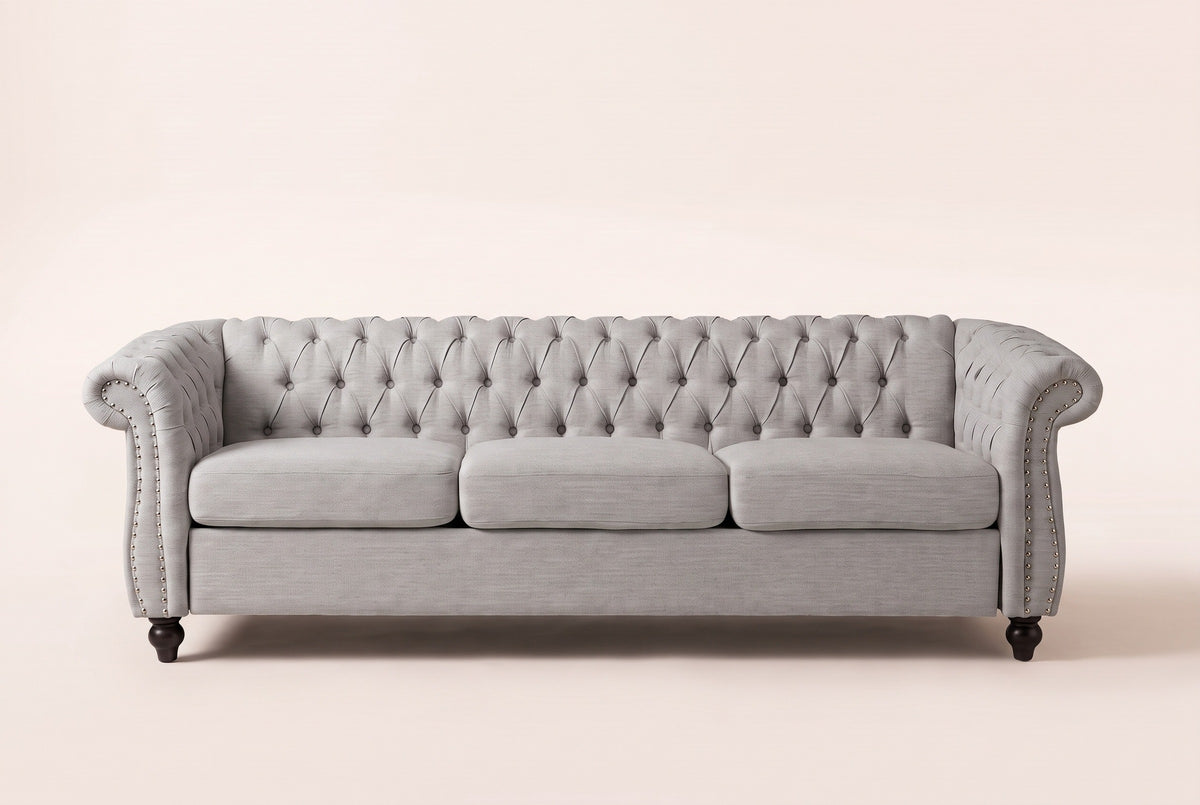 Portovenere sofa in grey, straight front view: a button-tufted back, three seat cushions, scrolled arms with silver nailheads