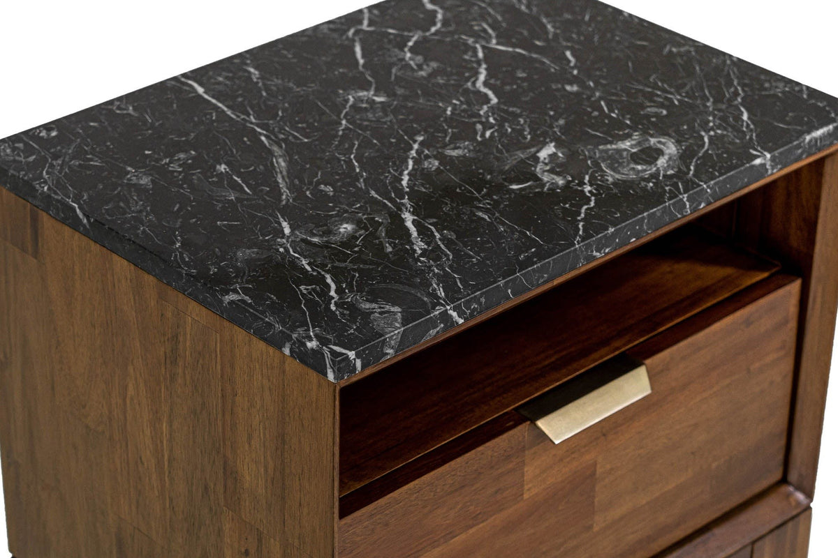 Close-up of the Postignano nightstand: the black marble top with white veins over the open niche and the brass tab pull on th