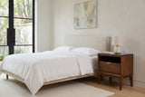 Postignano nightstand beside an oatmeal upholstered bed in a bedroom of an Outremont greystone house