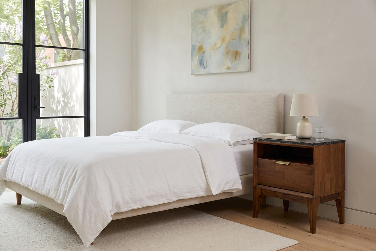 Postignano nightstand beside an oatmeal upholstered bed in a bedroom of an Outremont greystone house