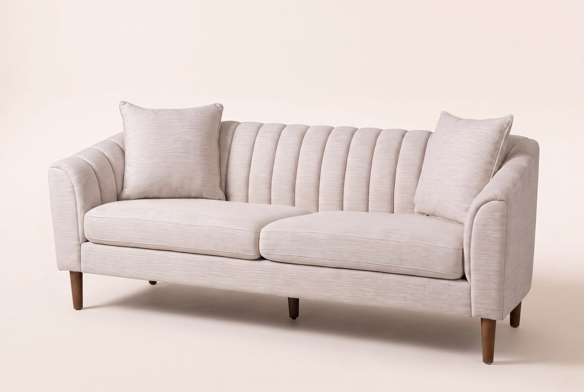 Prato channel-back sofa in beige on tapered wood legs, three-quarter view on a warm cream studio backdrop