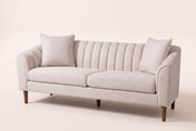 Prato channel-back sofa in beige on tapered wood legs, three-quarter view on a warm cream studio backdrop