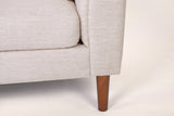 Close-up of the arm front and a tapered wood leg in a brown finish