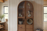 Prescott brown display cabinet holding glassware and baskets in a farmhouse room
