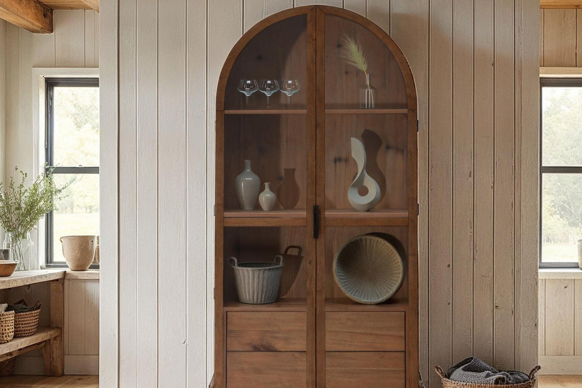 Prescott brown display cabinet holding glassware and baskets in a farmhouse room