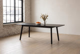 Prescott extension dining table in Antique Black opened to 86 in with clementines and dried grasses, in a brick loft in Winnipeg's Exchange District, snowy rooftops outside