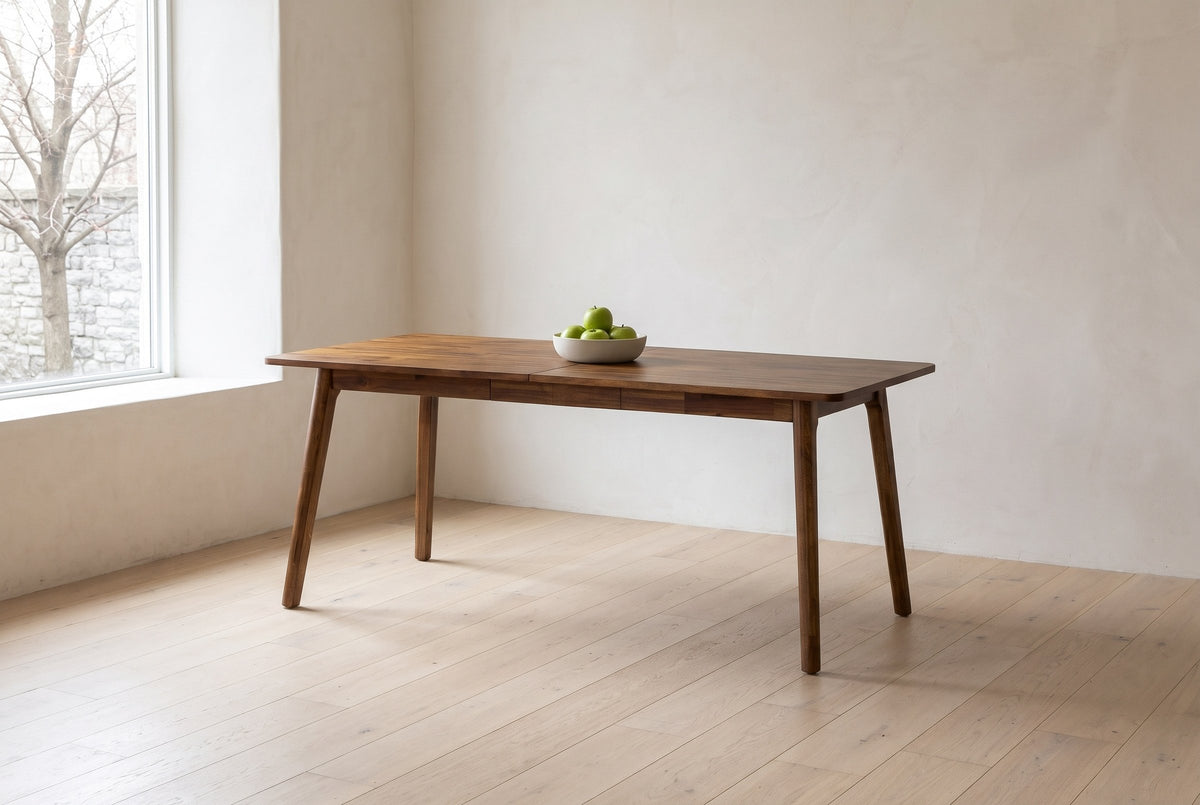 Prescott extension dining table in Brown with a bowl of green apples, in a plastered dining room of a Kingston, Ontario limestone house, a bare maple through the window