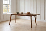 Prescott extension dining table in Brown opened to 86 in with bowls and bread, in a whitewashed farmhouse dining room in Prince Edward County, vineyard rows outside