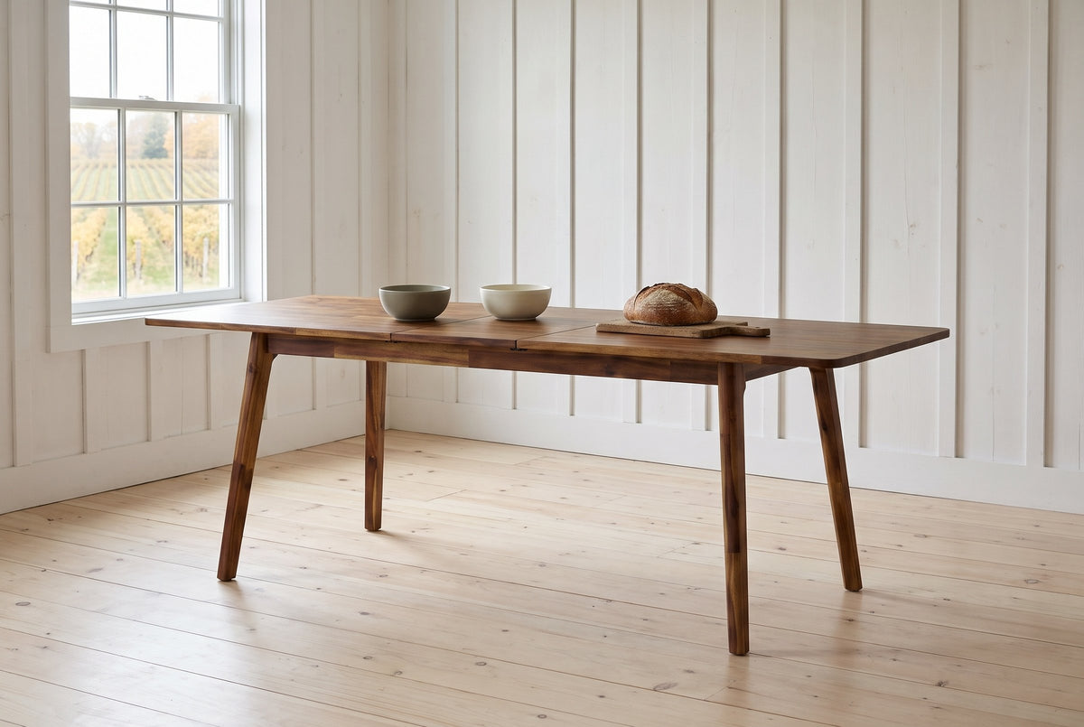 Prescott extension dining table in Brown opened to 86 in with bowls and bread, in a whitewashed farmhouse dining room in Prince Edward County, vineyard rows outside