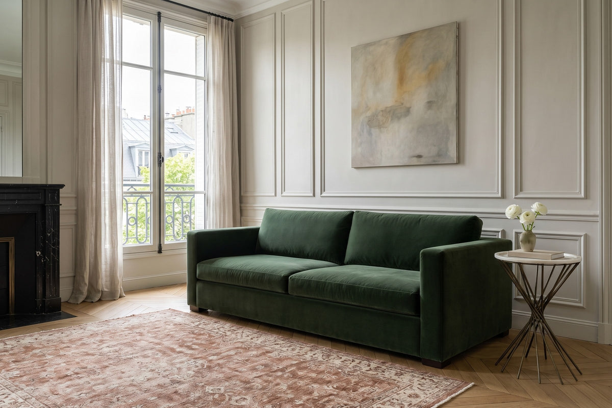 Rango side table at the arm of a forest-green velvet sofa in a Paris Left Bank apartment, with greige panelled walls