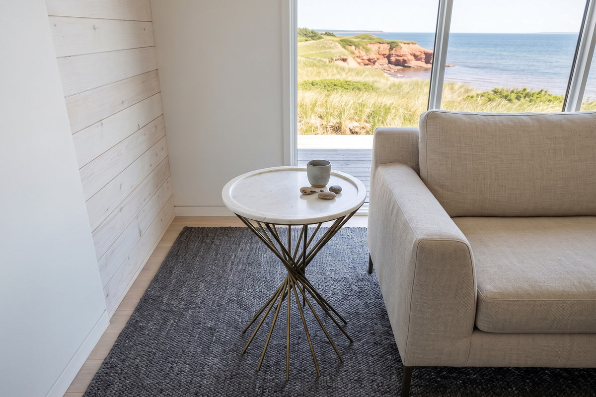 Rango side table seen from above beside a sand linen sofa in a Souris beach house, with whitewashed cedar boards