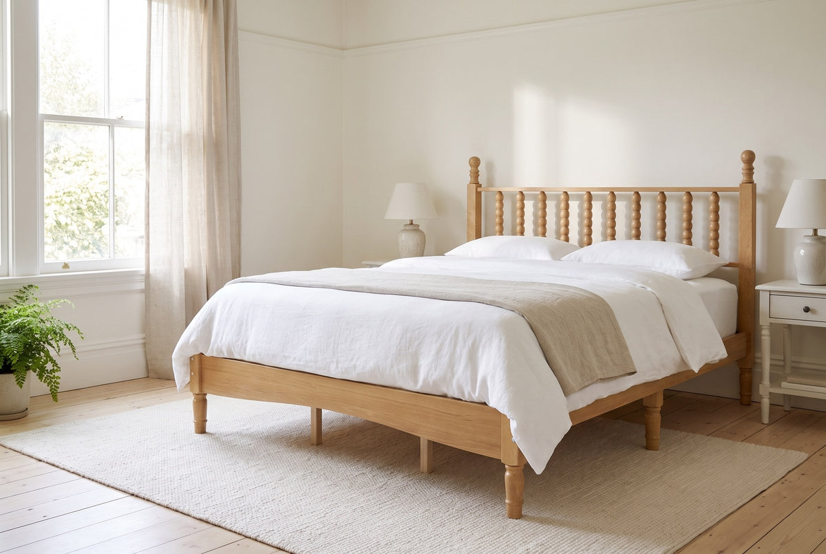 Ravenna spindle bed in Natural made up with white linen, in a bright heritage bedroom with a sash window and a fern