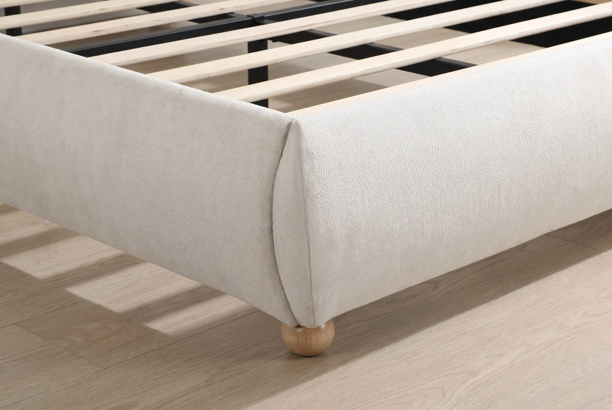Close-up of a domed foot corner in beige chenille on a solid oak ball foot, with the slats inside