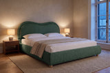 Recanati cloud bed in forest green chenille in a limewashed bedroom at dusk, two lamps lit on walnut nightstands
