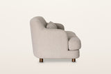 Ripatransone sofa in Beige, side view on a warm white studio backdrop: the back curves down into the arm and the seat cushion