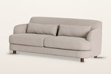 Ripatransone sofa in Beige, three-quarter view on a warm white studio backdrop: a tight curved back that sweeps into low roun