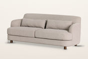 Ripatransone sofa in Beige, three-quarter view on a warm white studio backdrop: a tight curved back that sweeps into low roun