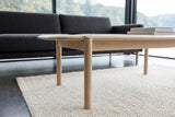 The Rivello legs in Light Oak at seat height: a round leg rising through the edge, the apron behind