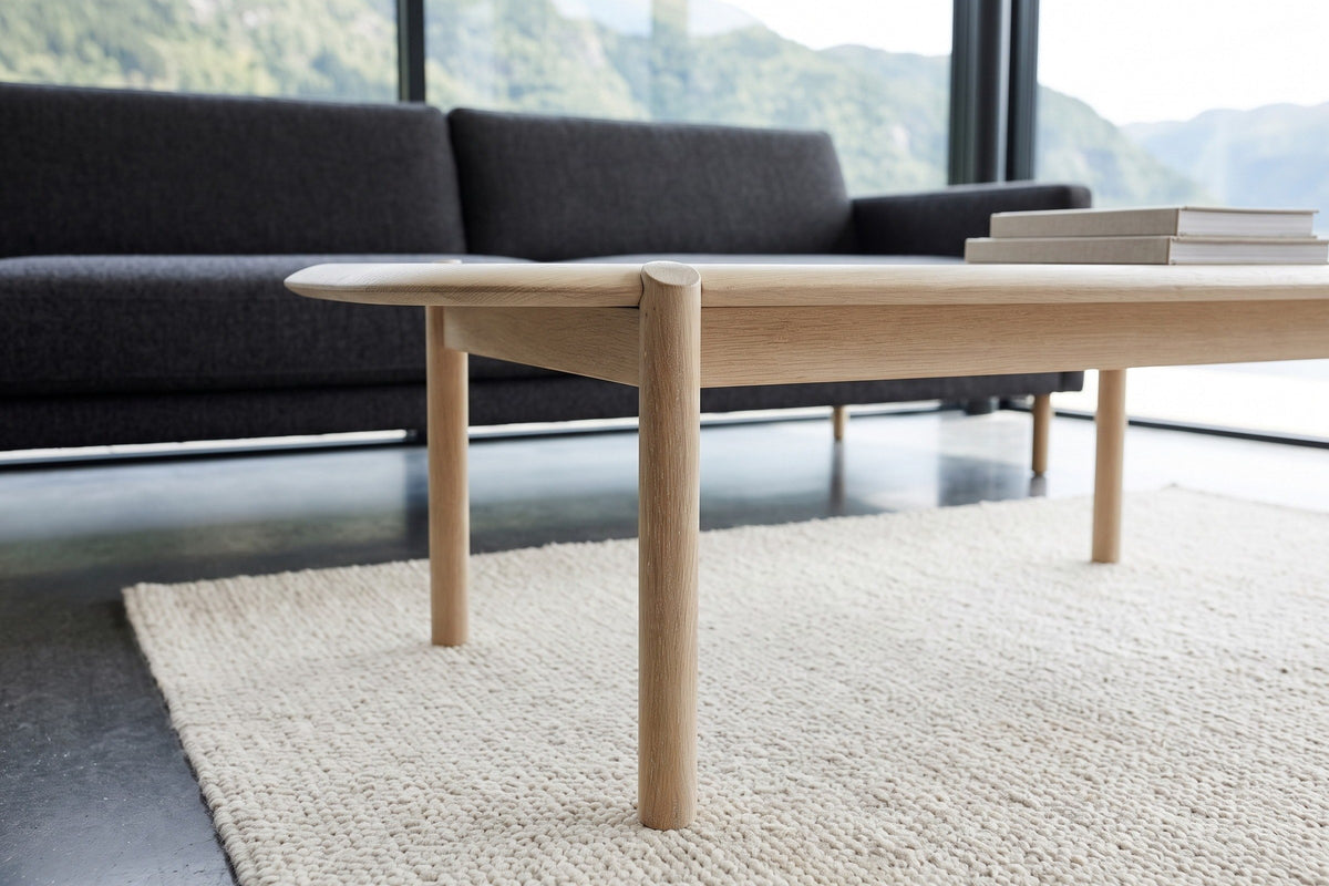The Rivello legs in Light Oak at seat height: a round leg rising through the edge, the apron behind