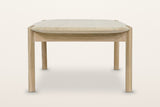 Rivello coffee table in Light Oak from the end on a warm white studio backdrop: two round legs