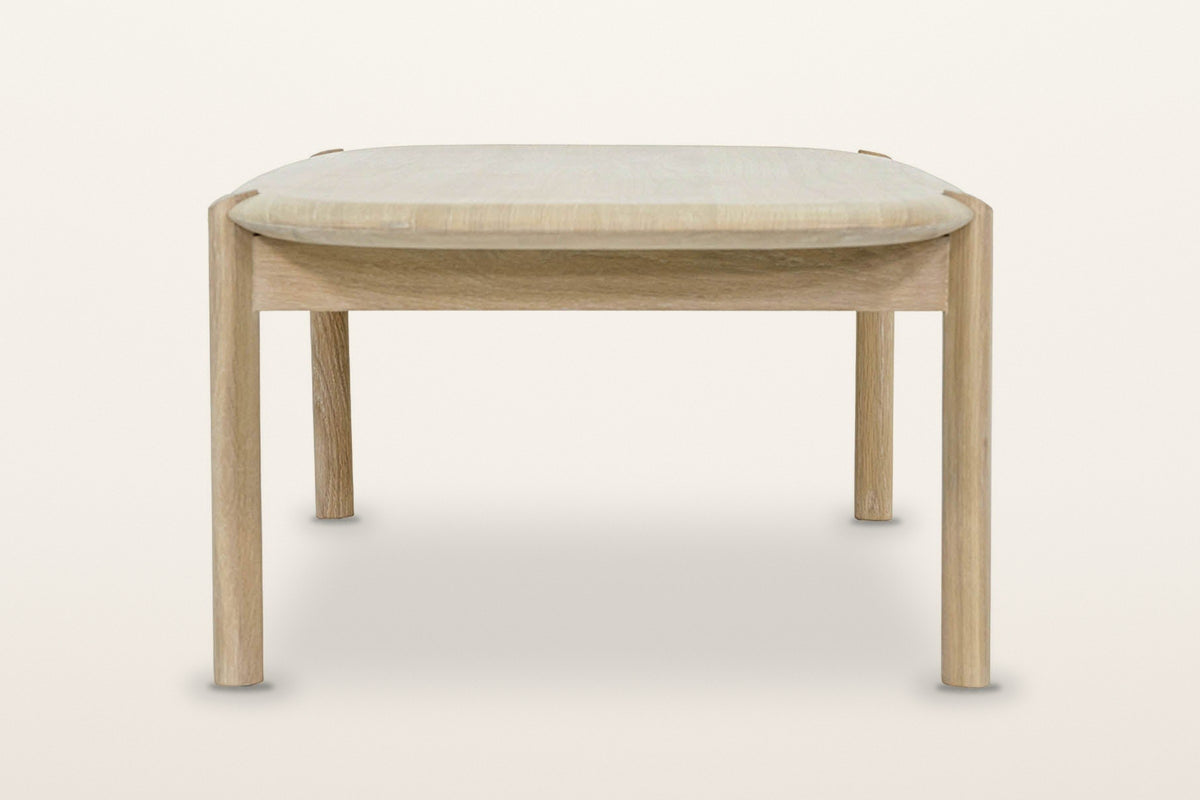 Rivello coffee table in Light Oak from the end on a warm white studio backdrop: two round legs