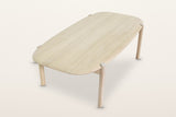 Rivello coffee table in Light Oak seen from above at the end on a warm white studio backdrop: the long top with its rounded c
